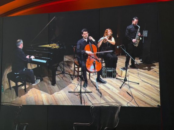 Frame della presentazione video di un saggio musicale con il maestro Luigi Mariani (al pianoforte) e altri musicisti coinvolti nell’esecuzione Frame della presentazione video di un saggio musicale con il maestro Luigi Mariani (al pianoforte) e altri musicisti coinvolti nell’esecuzione