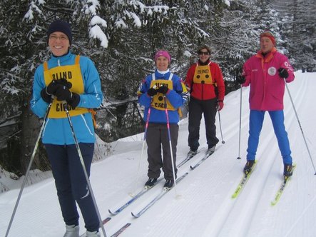 Alcuni partecipanti che sciano fra alberi bianchi di neve